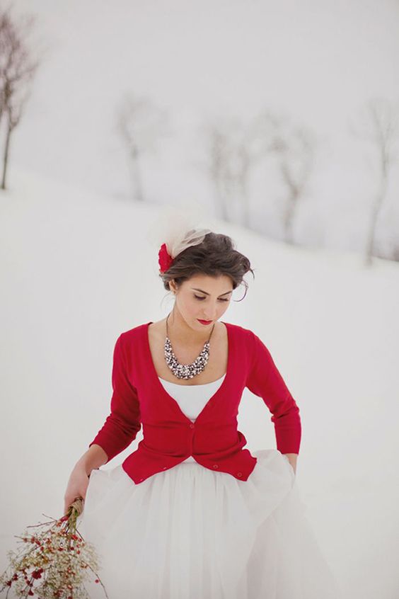 a short red cardigan and a statement necklace help to accessorize the wedding dress