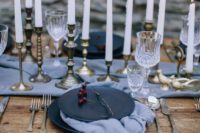 16 a moody coastal tablescape with a pale blue table runner and napkins, black plates and candles