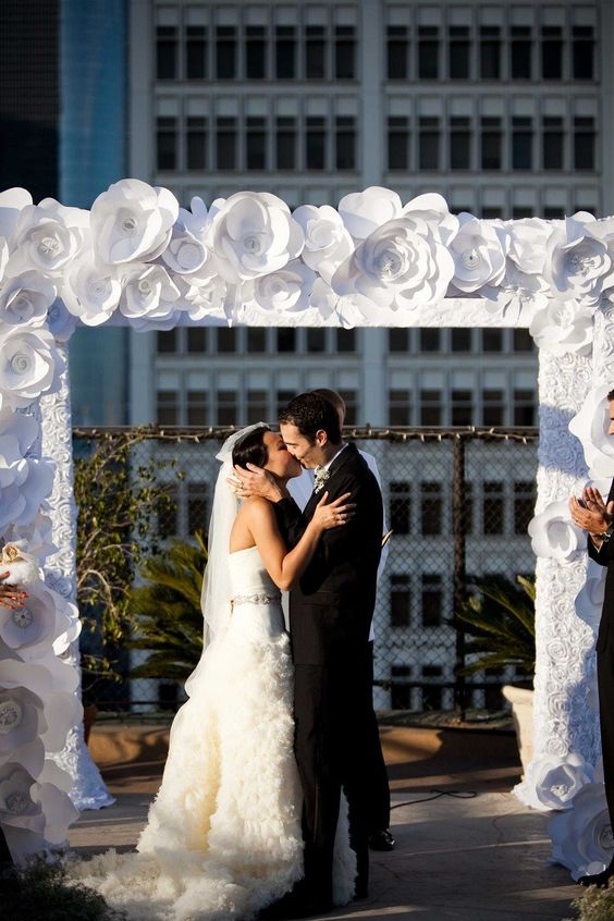 a white paper flower wedding arch is a great idea for a black and white wedding