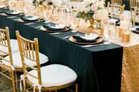 16 an elegant tablescape with a black tablecloth, a gold sequin table runner, gold vases and candle holders