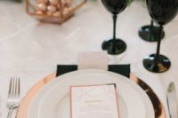 17 a modern glam place setting with a copper charger, black glasses, a copper lantern with candies and greenery