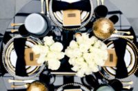 18 New Year’s Eve tablescape with a black table, napkin bows, gold cutlery and oversized ornaments