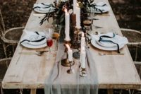 18 a moody table setting with an ethereal grey table runner, dark greenery, candles