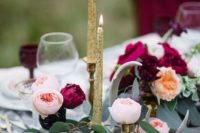18 gold candles, candle holders, plum-colored blooms and greenery for a luxe tablescape