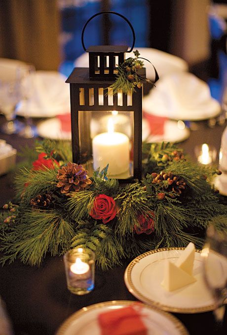 a candle lantern with a wreathof evergreens, red roses and pinecones for a rustic celebration