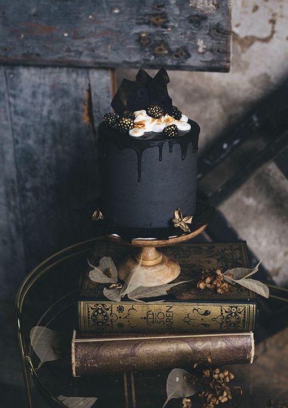 a matte black wedding cake with chocolate shards, gilded blackberries and cream