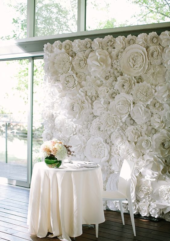 a white paper flower wall for the sweetheart table backdrop is a chic idea