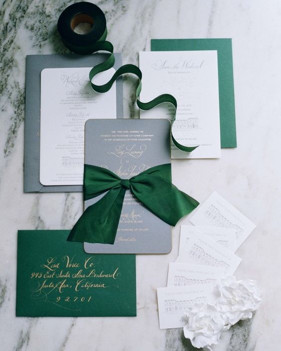 grey, white and emerald invitations with gold calligraphy and large bows remind of Christmas