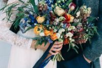 22 a lush textural bouquet with orange, blue, fuchsia and white blooms and various greenery looks impressive