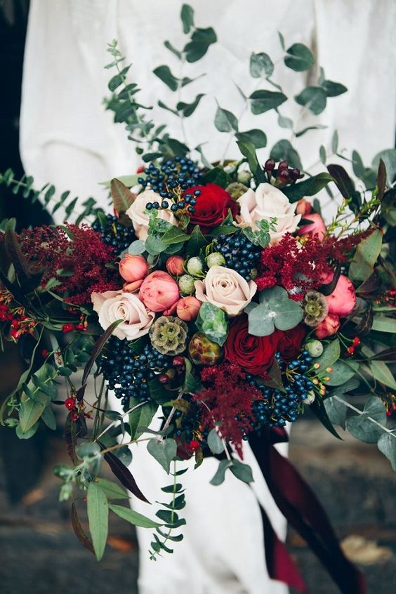 a lush textural bouquet with red roses, privet berries, eucalyptus, pink flowers and red foliage
