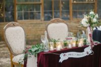 24 a luxurious sweetheart table with a burgundy velvet tablecloth, a greenery runner and candles