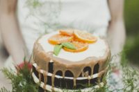 24 a naked wedding cake with caramel dripping, ferns and citrus slices