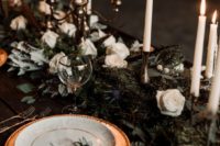 24 moody table decor with a pale runner made of thistles, white roses, evergreens and with gilded candle holders