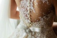 26 a wedding dress with a snowy back, lace appliques and a sash with a vintage brooch