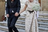 28 an ivory polka dot wedding dress with short sleeves and a black sash, matching shoes