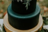 30 a winter wedding cake with a gold and black layers, evergreens and blooms