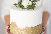 31 a small wedding cake with gold glitter, a white bloom and greenery on top