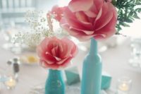 31 pink paper flower centerpiece with blue bottles as vases