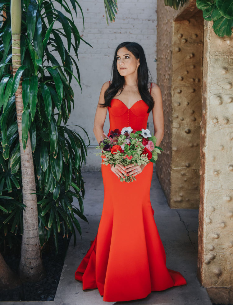 The bride was wearing a fiery red wedding dress with a mermaid silhouette, a train, a sweetheart neckline and a button row on the bodice