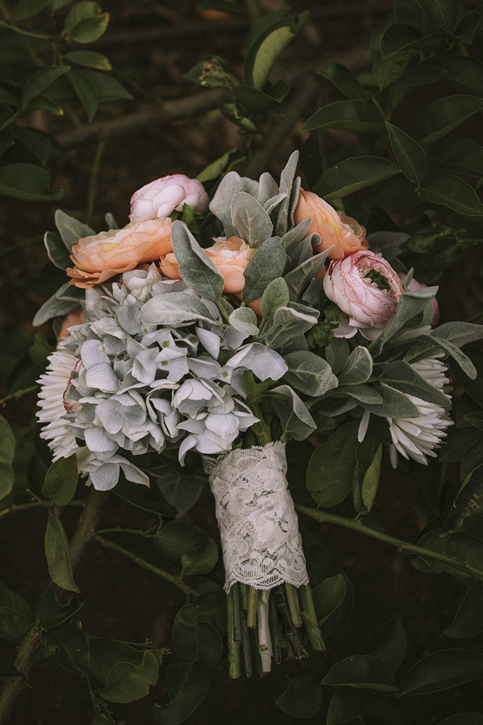 The wedding bouquet was done in pastel pink and orange, with pale greenery and a lace wrap