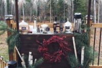 a gorgeous rustic hot chocolate bar with evergreens, birch branches, lanterns and a cool wreath