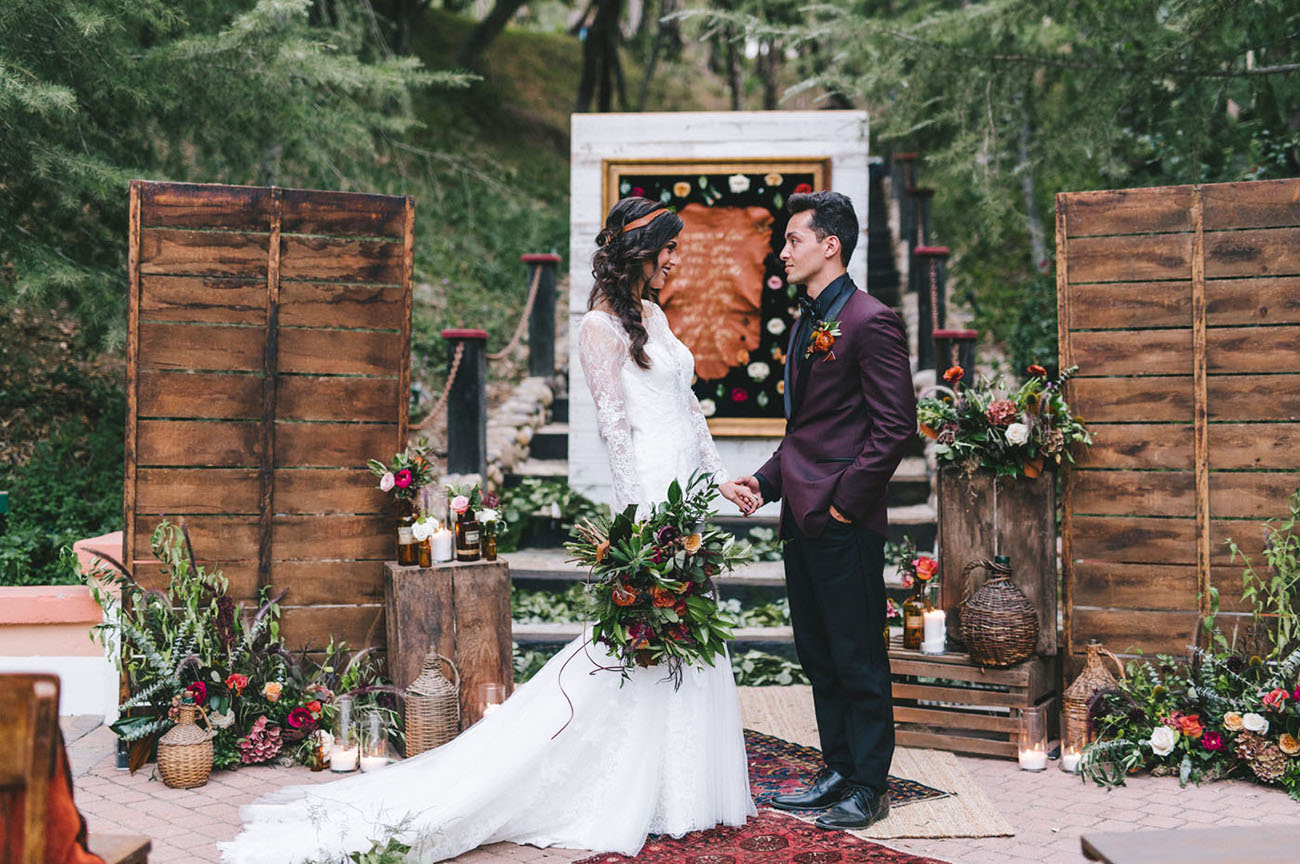 The wedding ceremony space was decorated in boho style, with wicker baskets, flasks, greenery, rugs and pallet wood