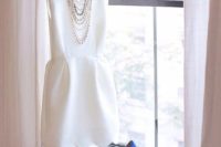 03 a modern plain sleeveless wedding dress with a high neckline and a scallop edge is completed with blue heels and statement necklaces