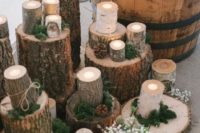 04 a rustic ceremony space with wood logs and candle holders, moss, pinecones and candles