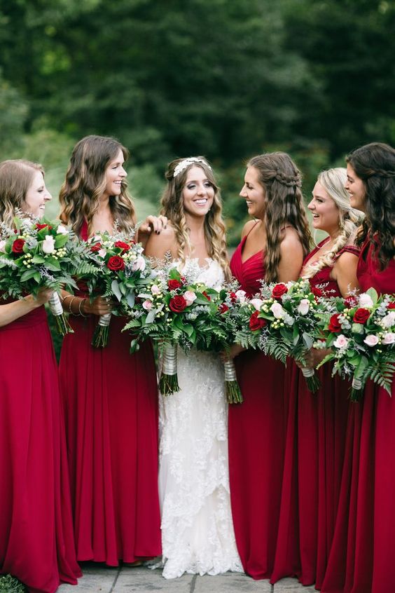 deep red bridesmaids' dresses and greeenry and red roses bouquets