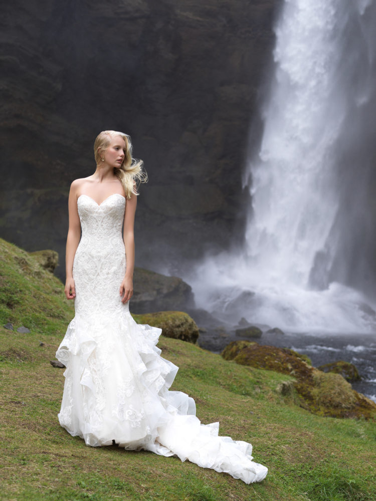 A strapless sweetheart neckline mermaid wedding gown of textural lace and with a ruffled tail and train