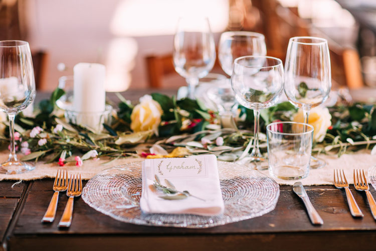 The wedding tables were decorated with foliage, blooms, candles and glass chargers