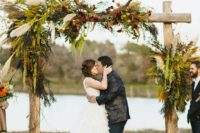 06 a boho wedding arch with lush greenery, pampas grass, fall-colored blooms and antlers