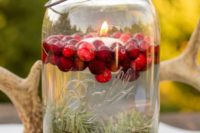 08 a floating candle in a jar with cranberries and evergreens looks very cute and cozy