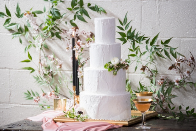 The wedding cake was a white frosted one with greenery, blooms served on a vintage mirror, with black ccandles and flowers in the backdrop