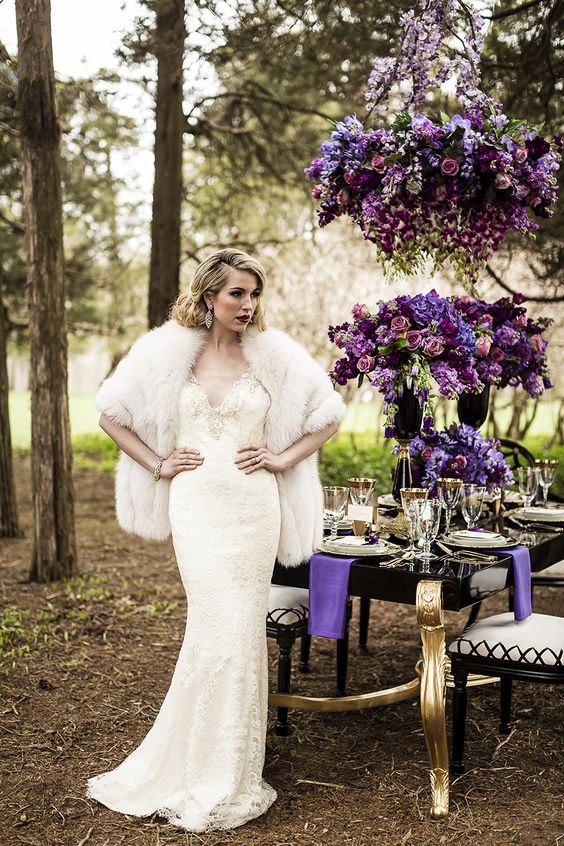 a lace and bead wedding dress with a V-neckline, a faux fur shawl and statement earrings for a glam look