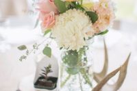 10 a rustic wedding centerpiece with a wood slice, a succulent, antlers and pastel blooms