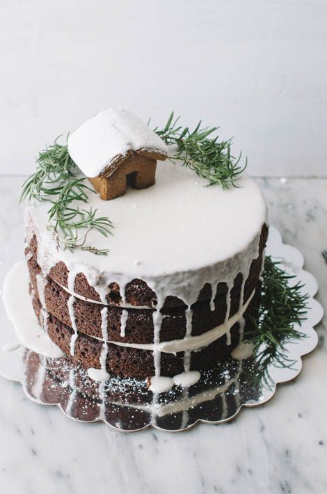 naked gingerbread wedding cake with icing, greenery and a gingerbread house with frosting