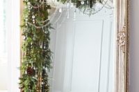 11 a gorgeous oversized vintage floor mirror with a fir garland, pinecones and crystals