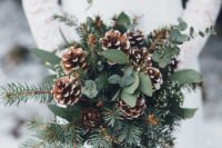 11 a wedding bouquet with evergreens, foliage and snowy pinecones for a winter boho or rustic bride