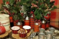 11 plaid thermoses are used as vases for antlers, evergreens and berries, plaid ribbons and plaid add winter charm
