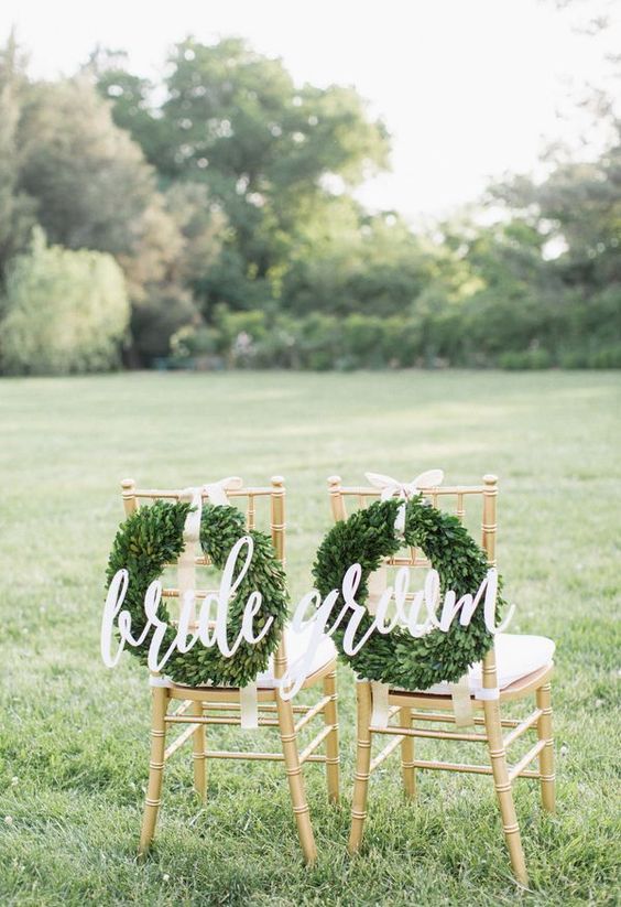 White calligraphy signs with lush boxwood wreaths and neutral ribbons are ideal for a Christmas wedding