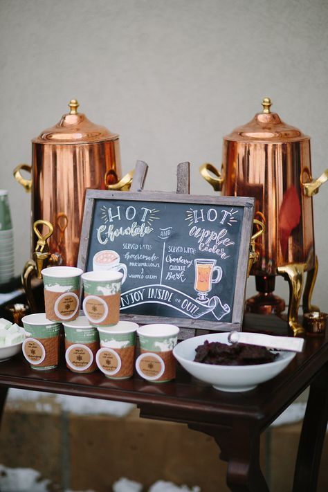a hot chocolate bar is decorated with copper tanks and a chalkboard sign for a cozy winter look