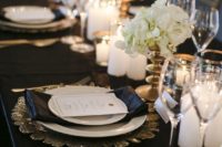 12 a stunning black and gold wedding tablescape with gold sunburst chargers, gold candle holders and vases