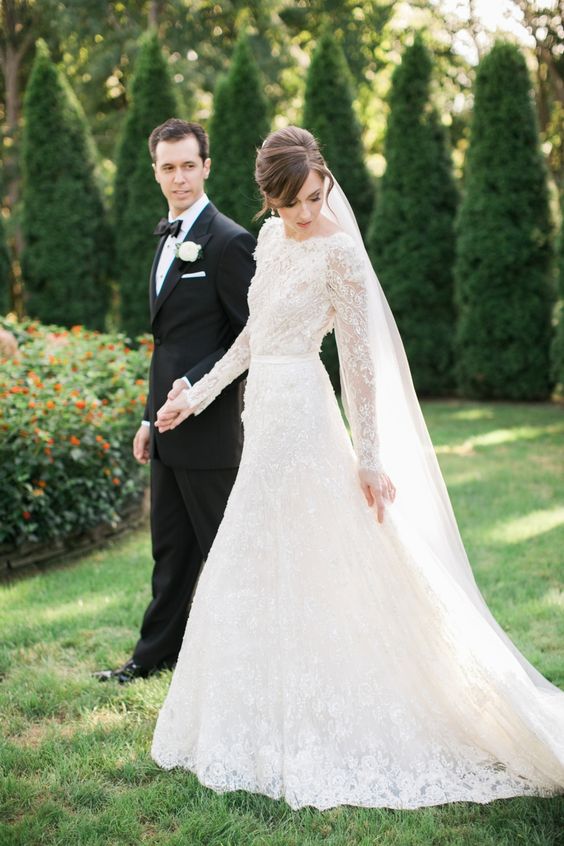 elegant long sleeve lace wedding dress with a bateau neckline and a small train, a veil finishes off the ensemble
