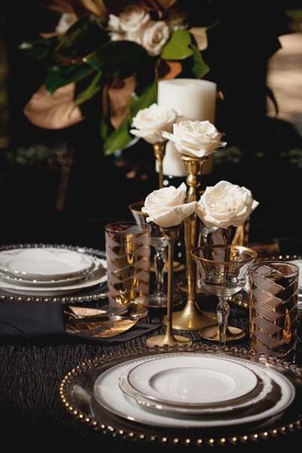 a refined tablescape with sparkly chargers, gold rim glasses and gold rose stands with white blooms