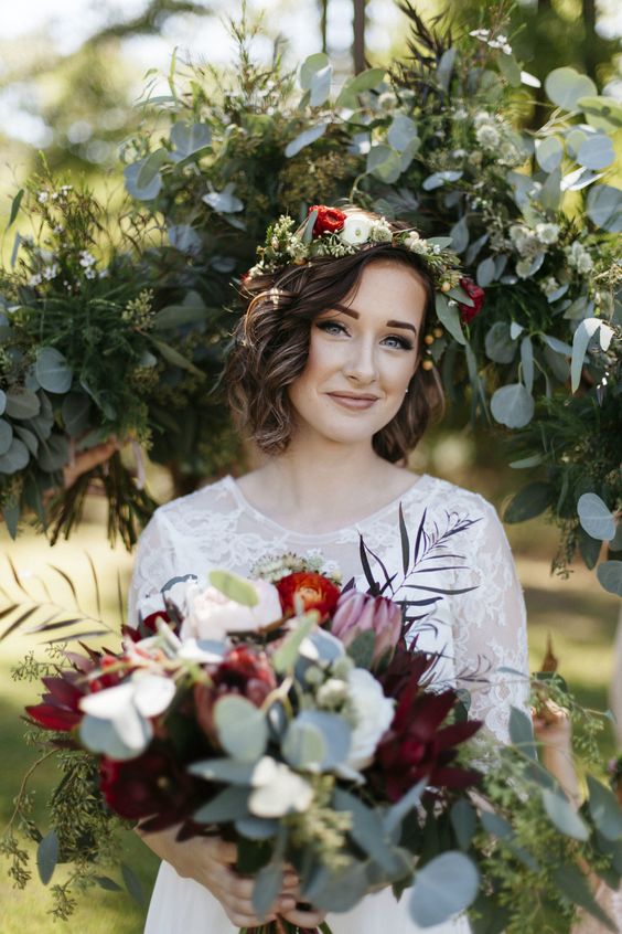 a messy wavy hairstyle accessorized with a fresh flroal headband of white, red blooms and greenery