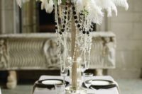 16 a black and white wedding table setting with black chargers and plates and a large feather, white rose and crystal centerpiece