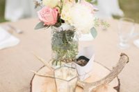 16 a rustic centerpiece with antlers, a candle holder, pastel and neutral blooms