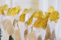 a feather escort card display with gold glitter looks bold for any wedding
