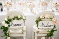 17 refined white signs with French words, greenery and blush blooms garlands add chic to the chairs